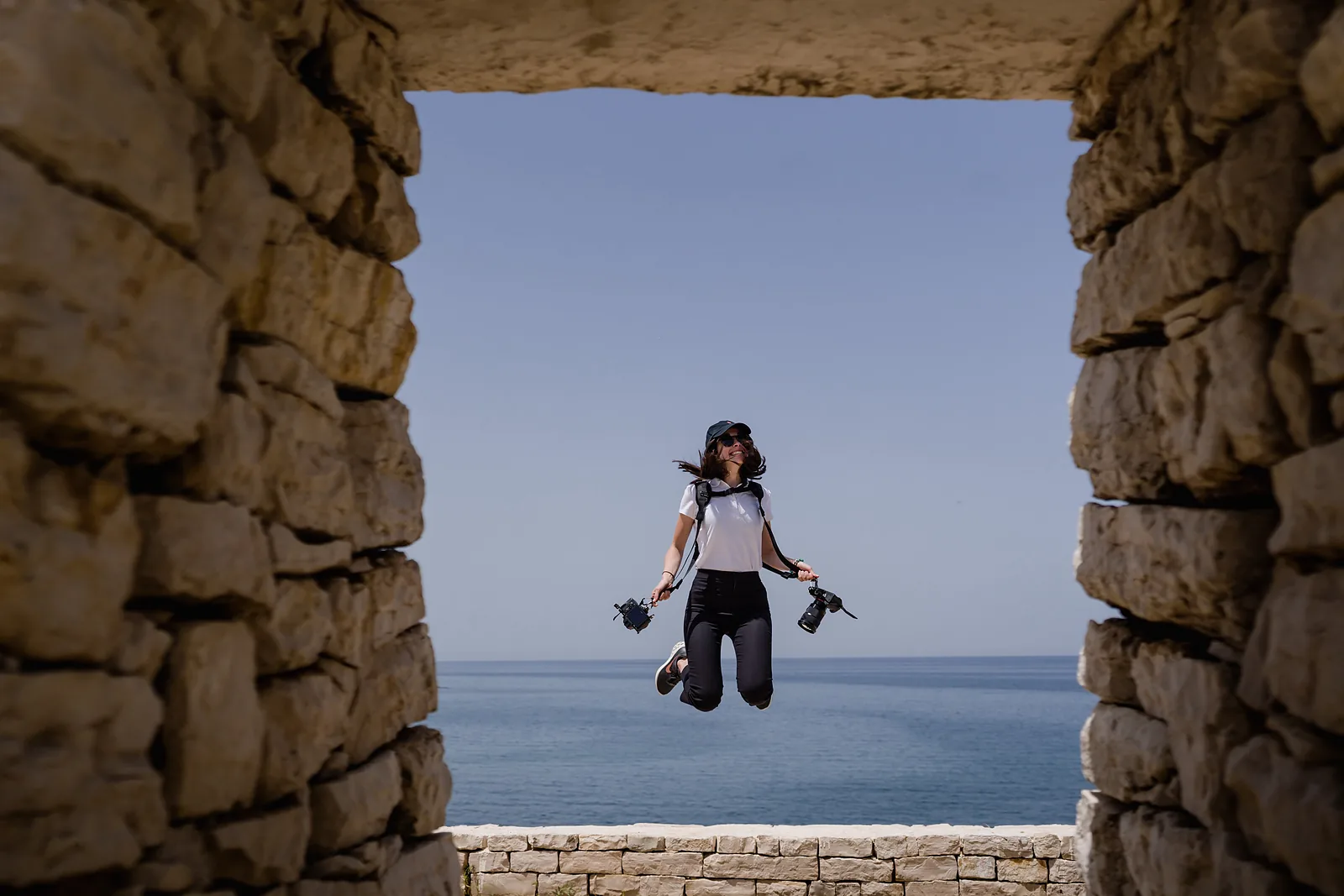 Fotografa del team ripresa in salto in una finestra di pietra sul mare