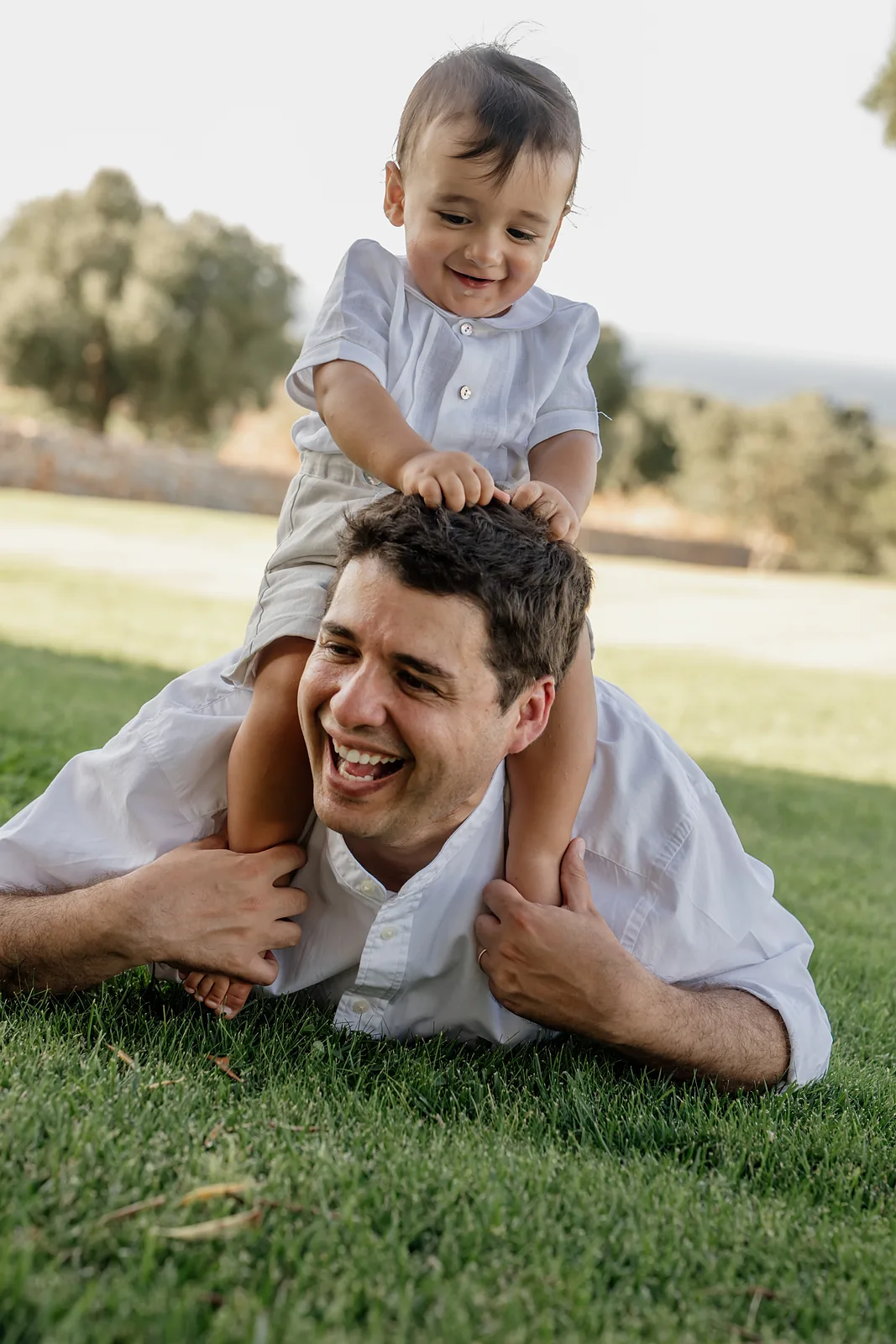 Papà gioca con il figlio sul prato durante uno shooting di famiglia