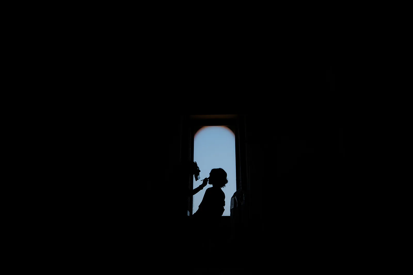Silhouette degli sposi in controluce nel vano di una finestra