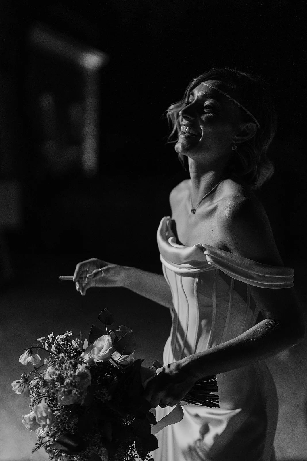 Ritratto in bianco e nero della sposa che ride con il bouquet